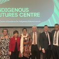 A group of men and women stand side by side on stage with a slide behind them reading Indigenous Futures Centre.